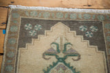 Vintage Oushak rug corner featuring beige stepped medallion design and emerald green motifs.