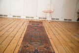 Lengthwise view of the vintage Karaja runner, displaying repeating gul motifs in brick red and navy.
