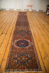 Hand-knotted Karaja runner's repeating gul motifs in brick red, navy blue, and teal.