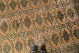 Distressed vintage Pakistan carpet, blanched pink ivory with dark Turkmen geometric pattern.