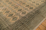 Secured corner of the blanched pink ivory rug, with dark green Turkmen border.