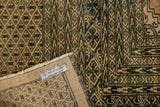 Distressed hand-knotted Pakistan carpet corner, with blanched pink ivory, dark geometric patterns, and fringe.