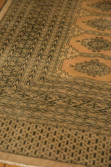 Hand-knotted Turkmen geometric border on a distressed pink ivory vintage Pakistan rug.