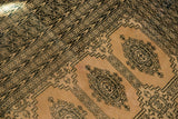 Geometric black border and Turkmen patterns on a distressed blanched pink ivory rug.
