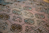 Distressed texture of dusty blush Bokhara gul motifs with blue and charcoal accents.