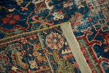 Secured edge and distressed texture of a vintage Heriz rug in blue and cherry red.