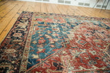 Angled detail of distressed vintage Heriz rug texture with geometric sapphire blue and cherry red.