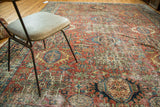 Distressed texture and repeating geometric medallions on a Karaja rug in brick red and jewel tones.
