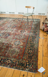 Distressed vintage Karaja carpet with multi-medallion pattern, brick red field, and navy border.