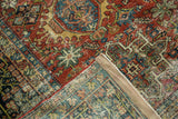 Folded corner of distressed Karaja rug showing brick red geometric patterns and secured binding.