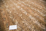 Distressed Qom rug's worn texture, highlighting soft ivory, brown, and blush channel motifs.