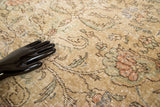Textured distressed vintage Oushak rug with faded scrolling floral motifs in beige, green, and blush.