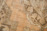 Distressed apricot peach and brown curvilinear patterns on a vintage Oushak carpet.
