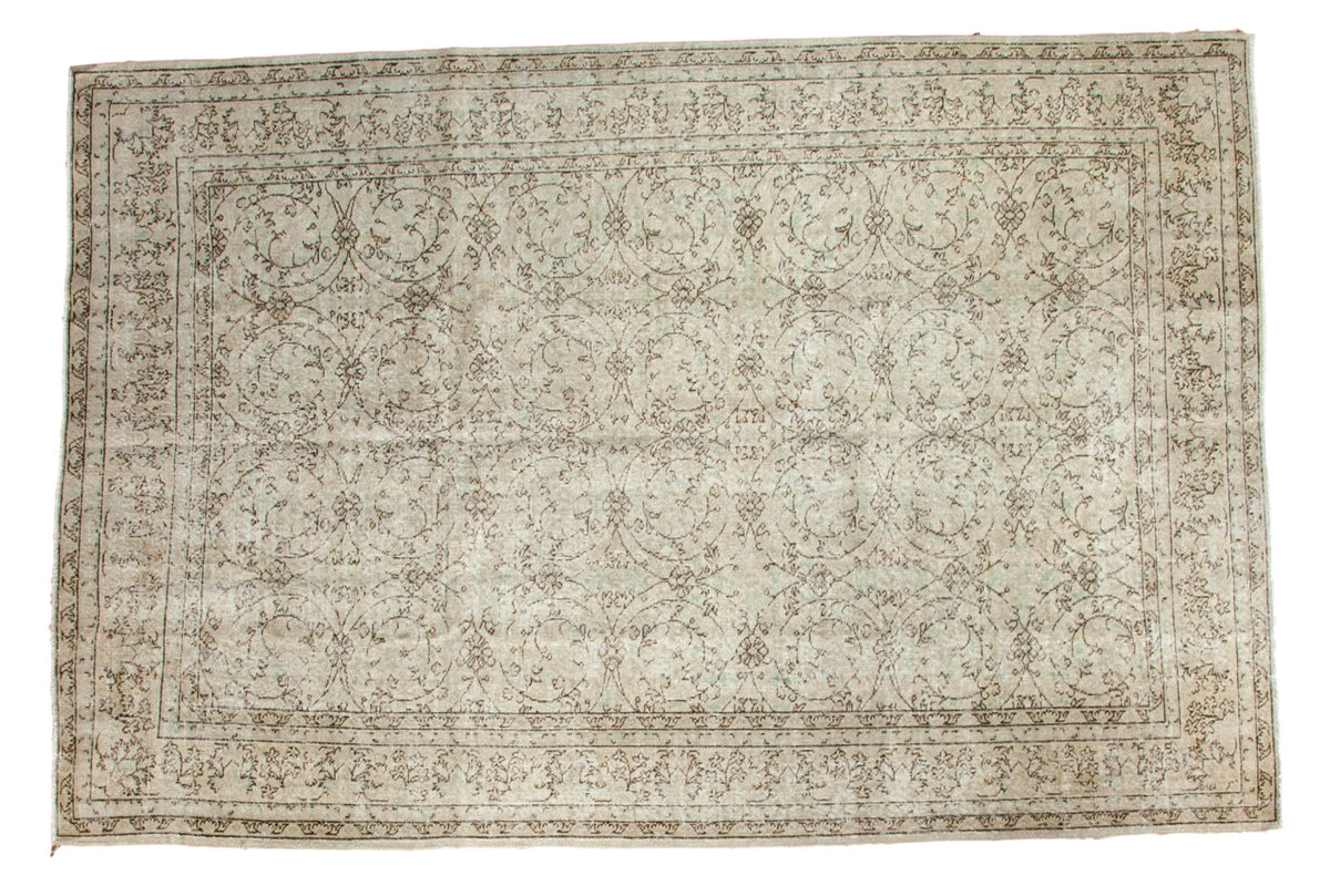 Distressed vintage Oushak rug with allover scrolling floral pattern in muted ivory and brown.