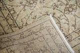 Distressed vintage Oushak carpet with faded floral motifs and hand-knotted foundation.
