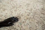 Distressed Oushak carpet's faded pile reveals antique ivory, beige, brown floral vines, celadon green.