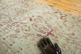 Hand showing distressed pile texture and cochineal patterns of vintage Oushak runner.