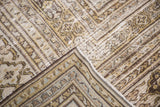 Distressed vintage Khorassan rug corner revealing textured pile and soft charcoal, cream, silver patterns.