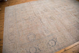 Corner of a distressed Oushak rug with faded pink ivory and slate blue floral motifs.