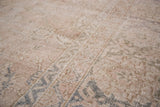 Distressed pile of a vintage Oushak rug with faded pink ivory and slate blue floral motifs.