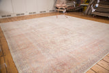 Distressed vintage Oushak rug with soft cream, pink, and lavender curvilinear patterns.