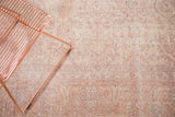 Distressed vintage Oushak rug texture with muted cream, pink, and lavender floral patterns.
