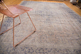 Textured detail of distressed Oushak rug's beige field and violet decorative pattern.