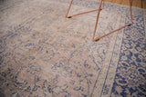 Worn texture on a distressed vintage Oushak rug with beige field and violet border.