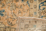 Hand-knotted foundation and distressed floral pile in peach, ivory, and blue.
