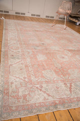 Distressed Oushak rug corner with faded crevette pink, ivory, and seaglass blue motifs.