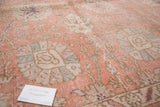 Distressed vintage Oushak carpet texture, revealing faded crevette pink and seaglass blue motifs.