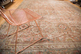 Distressed vintage Mahal rug with muted terra-cotta and faded pastel floral patterns.
