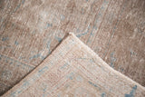 Distressed Sivas rug fold, revealing hand-knotted foundation and soft blue hints.