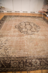 Distressed Oushak rug corner with dark brown border and worn slate silver motifs.