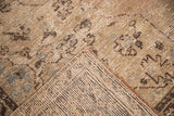Distressed vintage Oushak rug's muted beige pile, blue motifs, and hand-knotted foundation.