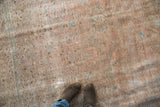 Distressed vintage Kashan rug texture with faded bronze, dark rose, and aqua blue motifs underfoot.