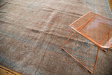 Textured distressed vintage Kashan rug in muted bronze and aqua, with modern copper chair.