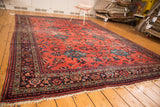 Distressed vintage Mahal carpet corner, highlighting dark blue border with colorful floral motifs and fringe.
