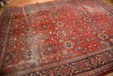 Distressed vintage Mahal rug corner, bold cherry red field, dark border, and worn pile.