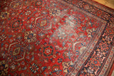 Distressed cherry red field of a vintage Mahal, highlighting worn texture and intricate motifs.