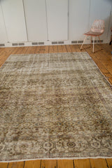 Distressed Oushak rug corner with intricate faded vinery and floral patterns.