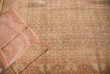 Textured detail of the distressed vintage Tabriz carpet's faded rust and brown border design.