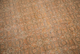 Distressed vintage Tabriz carpet showing faded rust motifs and worn pile revealing knot heads.