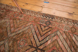 Textured hand-knotted Vintage Kurd rug showing rust, brown, slate blue zigzags, and secured edge.