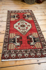Hand-knotted Oushak rug's cherry red field and geometric plant-in-vase design.