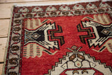 Vintage Oushak rug detail: cherry red field, dark charcoal germinating plant motif, geometric border.