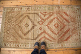 Distressed vintage Afghani rug corner with terracotta, copper, and beige geometric patterns.
