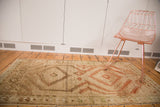 Distressed geometric medallion motifs in sage, gold, and terracotta on the Afghani runner.