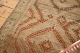 Finely woven distressed Afghani rug section, faded geometric patterns in beige and terracotta.