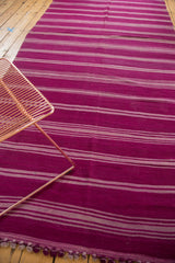 Repeating horizontal aubergine and gray stripes on a vintage Moroccan Kilim rug with tasseled ends.